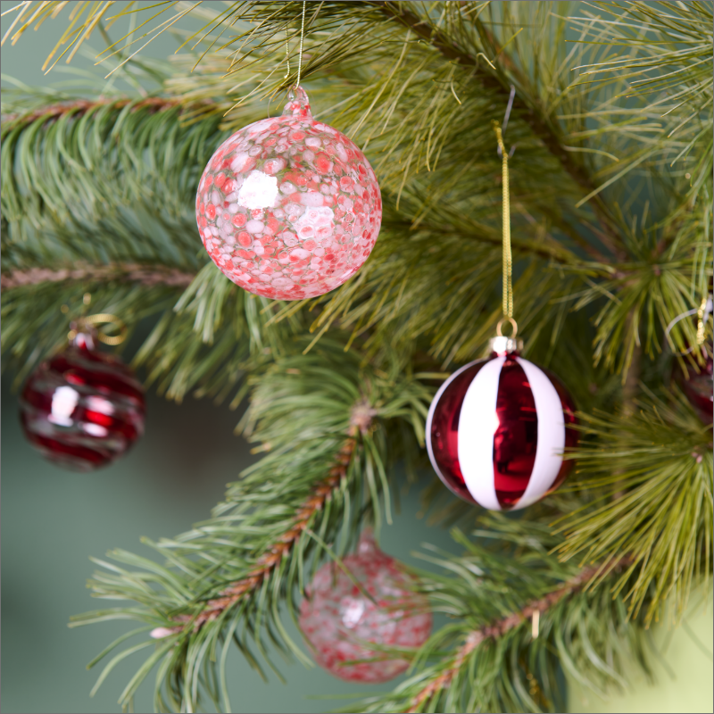 Rot-gemusterte Christbaumkugeln an einem Weihnachtsbaum.