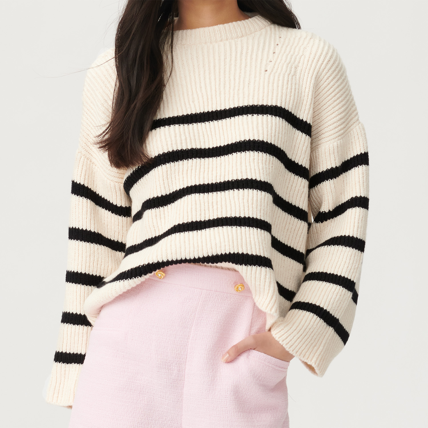 Strickanleitung gestreifter Pullover aus Fashion Cottony: Weißer Pullover mit schwarzen Streifen, kombiniert mit rosa Hose. Ideal für modische Outfits.