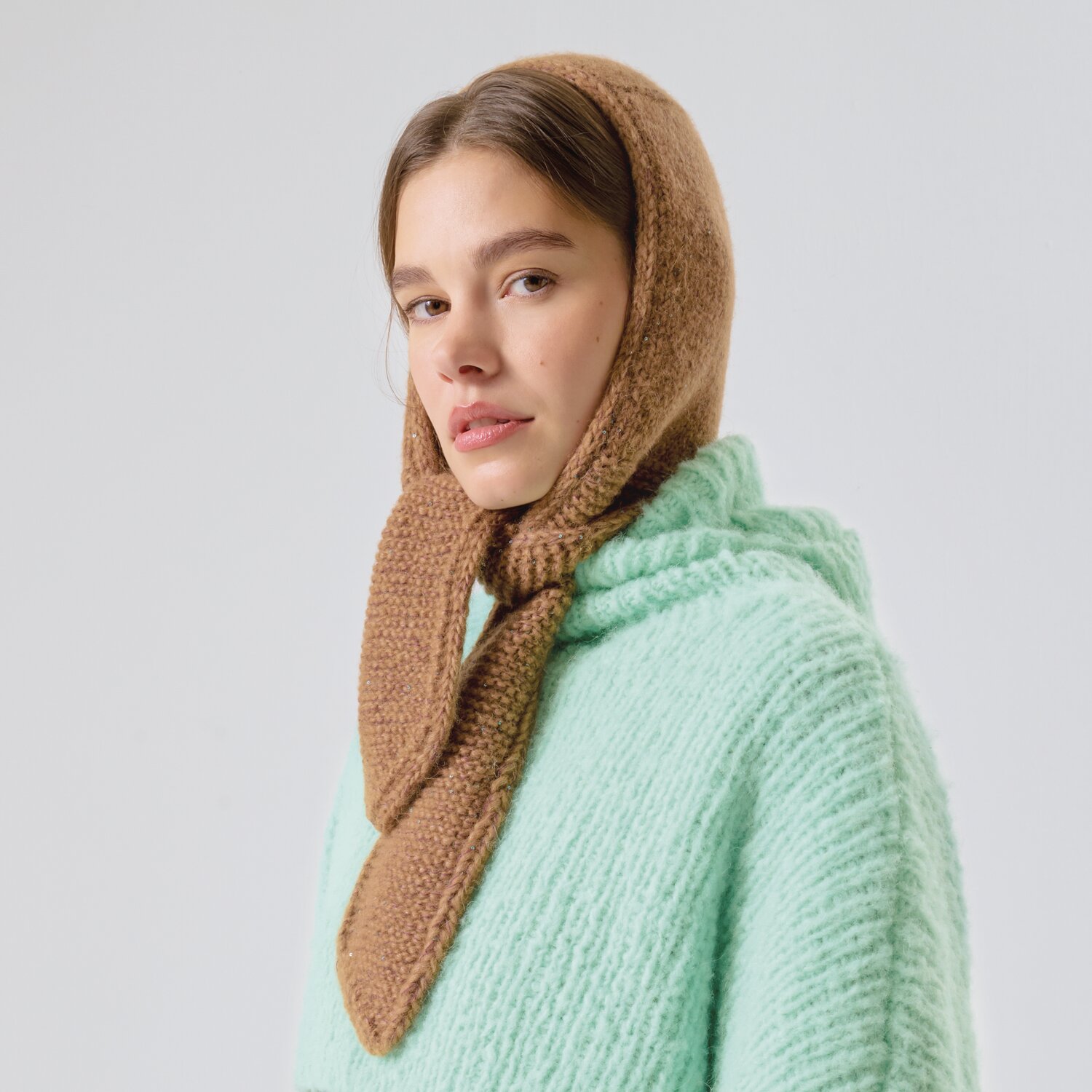 Strickset Kapuzen-Mini-Tuch Modell 16 aus Made by Me No. 21 von Rico Design Strickset Kapuzen-Mini-Tuch Modell 16: Frau trägt braunes Tuch und mintgrünen Pullover. Ideal für kühle Tage.