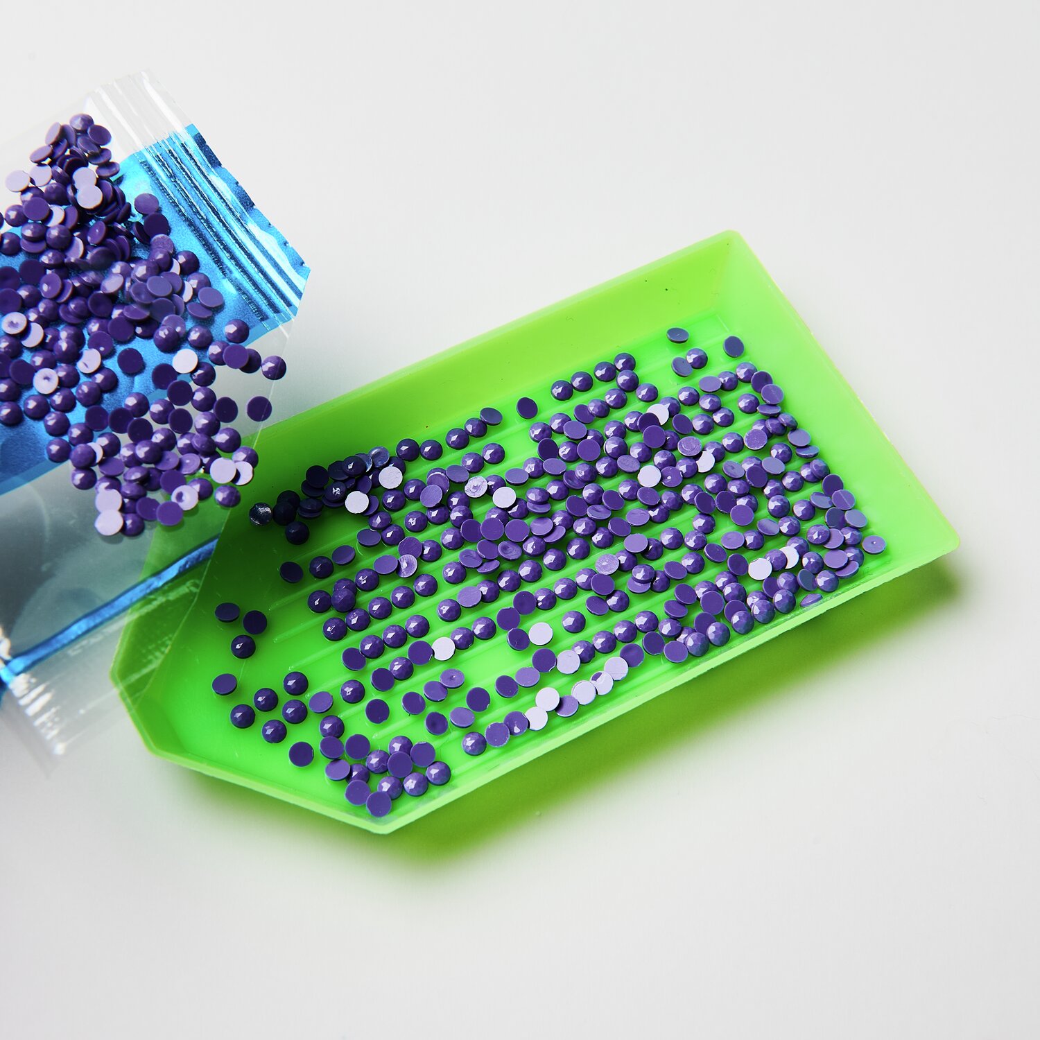 Diamond Painting DIY-Set Schimmernde Blumen 19-teilig: Lila Steinchen auf grünem Tablett für kreatives Basteln. Ideal für detailreiche Kunstwerke.