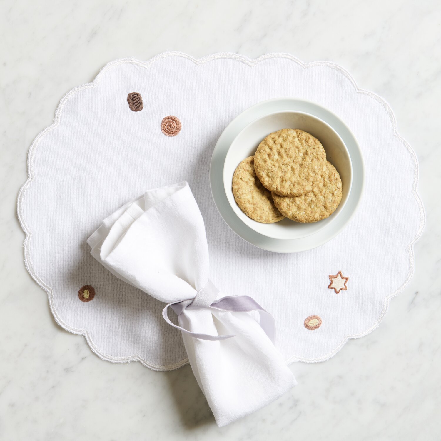 Platzsets oval Weiß 2 Stück, dekoriert mit Keksen und Serviette, auf einem Tisch arrangiert.