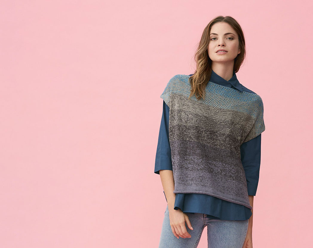 Eine Frau trägt einen dunklen gestrickten Pullunder, aus einem Farbverlaufsgarn und steht vor einer pinken Wand.