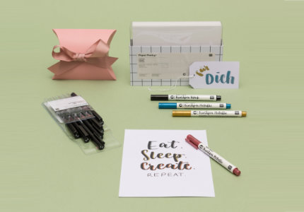 Weiße Karten in der Verpackung, eine Geschenkschachtel, eine beschriftete Karte und Geschenkanhänger mit Brushpens und verpackten Pigment Linern.