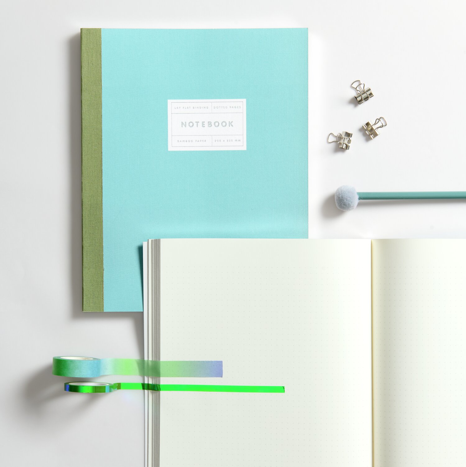 Paper Poetry Notizbuch L in Mint mit Bleistift und Pompon, grün-blaues Tape, silberne Klammern.