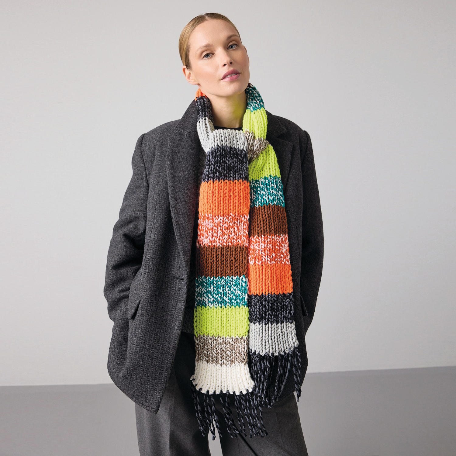 Garnset „Schal des Jahres“: Frau trägt bunten Schal in Orange, gestrickt mit Wolle Rödel.