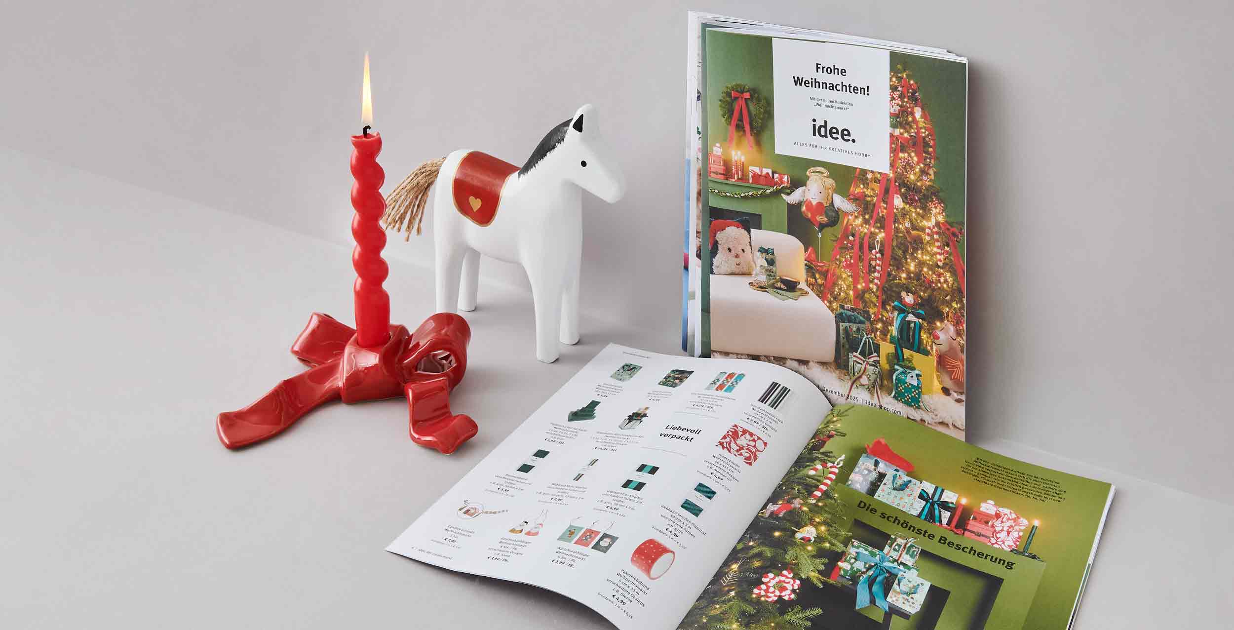 Prospekt Titel und aufgeschlagen, Kerzen und Holzpferd stehen daneben