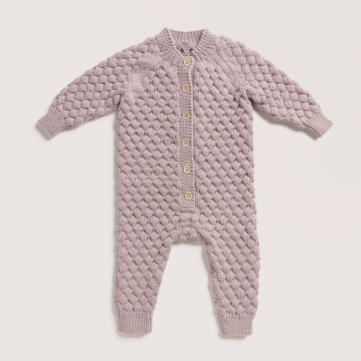 Rico Baby 042 Sprachauswahl deutsch von Rico Design Strickset Strampler Modell 04 in Flieder, gestrickt aus Rico Baby Dream dk uni, zeigt ein luxuriöses Design mit Knopfleiste.