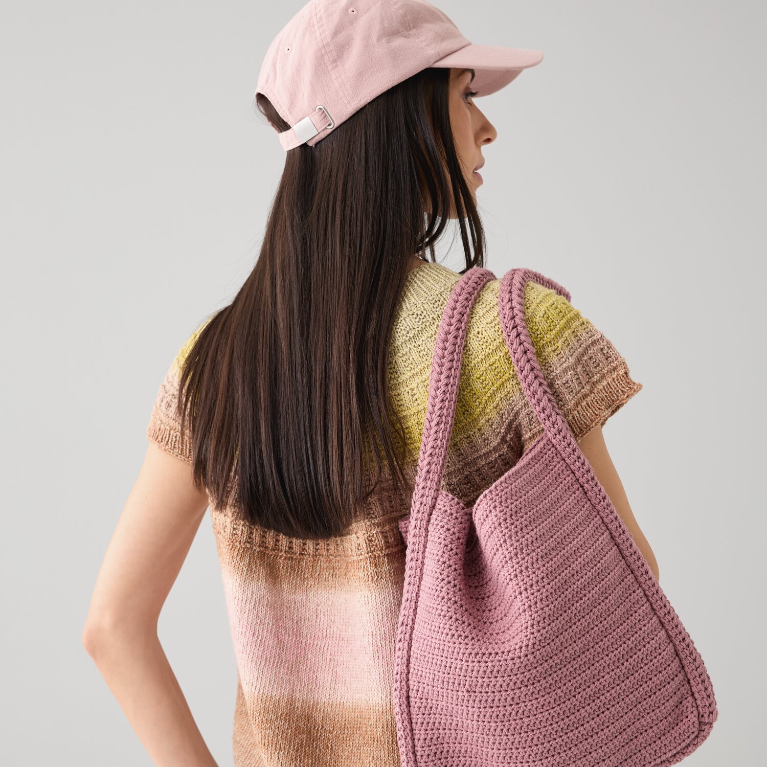 Häkelset Shopper Modell 18 B: Frau mit rosa Tasche und Mütze, trägt gestreiftes Oberteil.