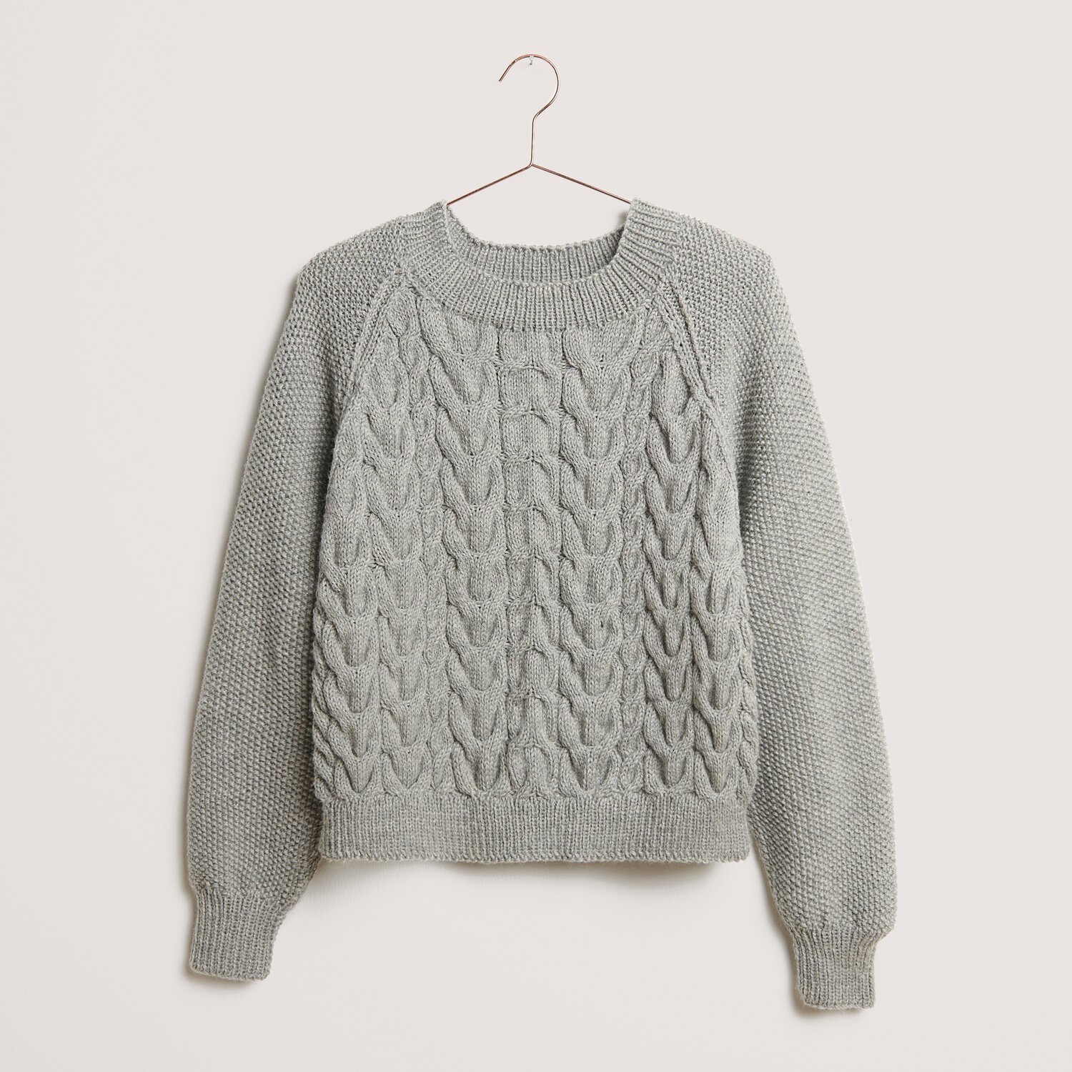 Die Neue Masche No. 14 Winter von idee. Creativmarkt Essentials Soft Merino aran Pullover in Hellgrau mit Zopfmuster, gestrickt aus weicher Wolle. Ideal für kühle Tage, stilvoll und bequem.