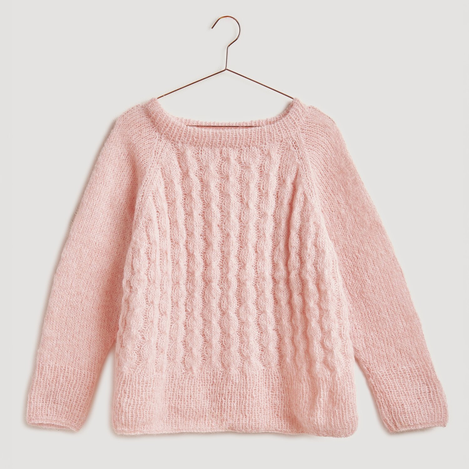 Die Neue Masche No. 13 Herbst von idee. Creativmarkt Strickset Pullover Modell 07 aus Die Neue Masche No. 13, apricot, mit Zopfmuster, auf einem Bügel. Ideal für Herbstmode.