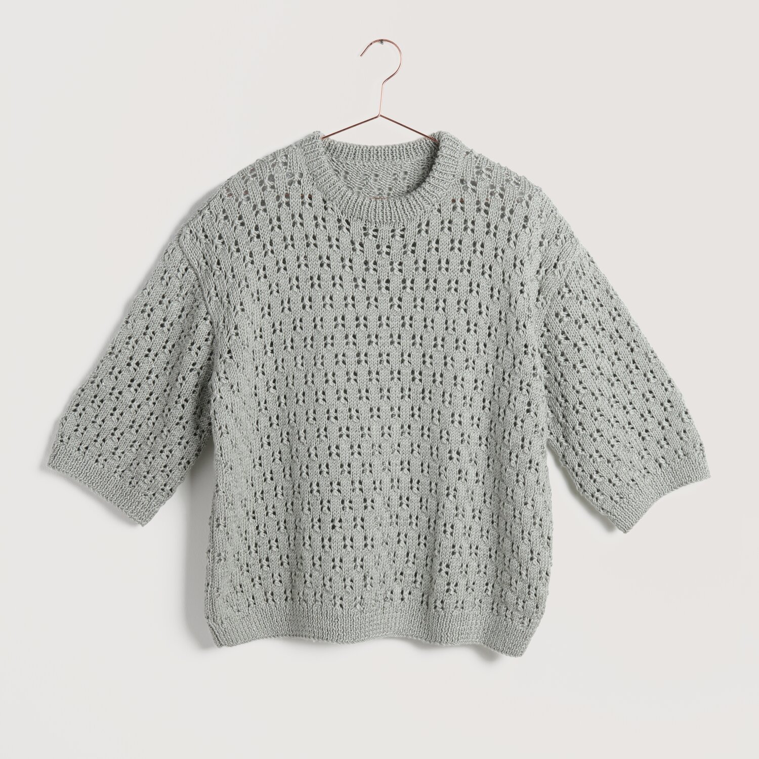 Creative Silky Touch dk Pullover in silbergrau mit Lochmuster, hängend an einem Kleiderbügel.