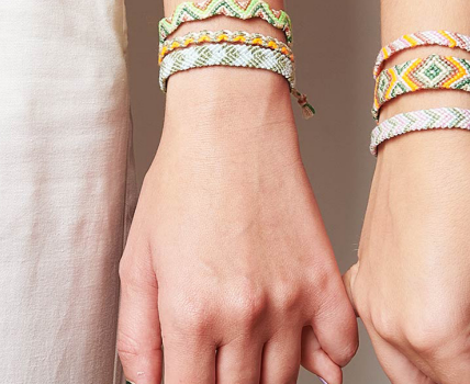 Bunte, selbst geknüpfte Freundschaftsarmbänder an zwei Handgelenken.