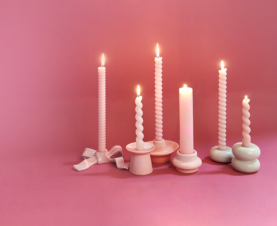 verschiedene rosa Stabkerzen stehen in Kerzenhaltern