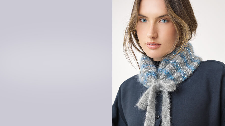 Frau mit blau-grau gemustertem gestricktem Tuch um den Hals vor hellem Hintergrund
