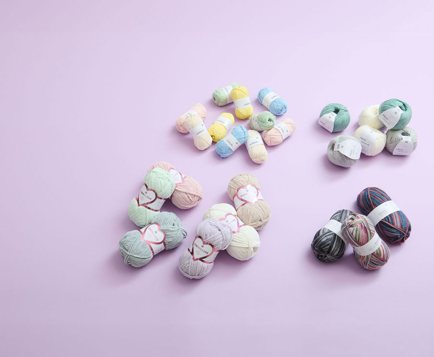 Unterschiedliche Wolle zusammenliegend auf kleinen Haufen und lila Hintergrund. Flatlay von Produkten.