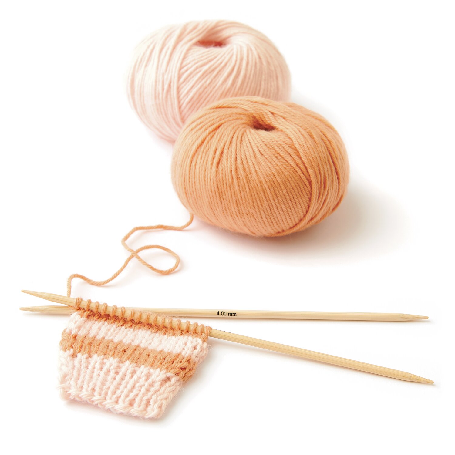 Rico Baby 042, Rico Baby Dream dk uni - A Luxury Touch: Zwei Wollknäuel in Apricot und Lachs mit Stricknadeln und Strickprobe.