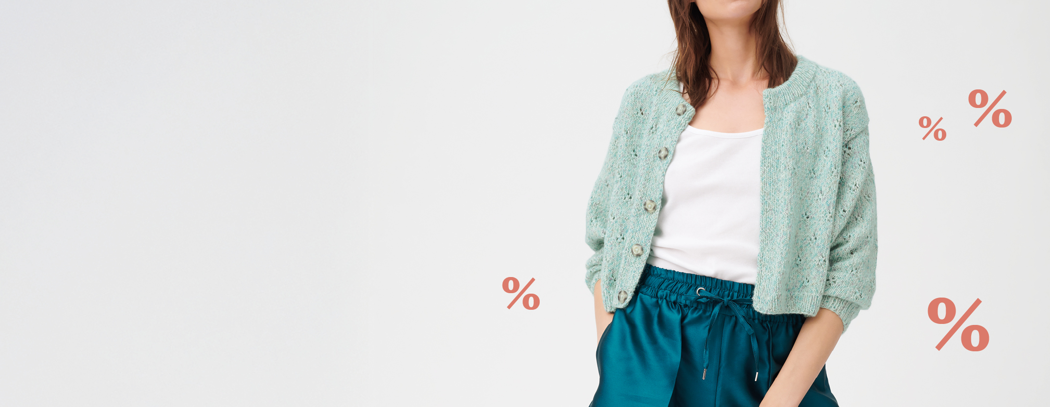 Frau trägt türkisfarbenen Cardigan, im Hintergrund %-Zeichen