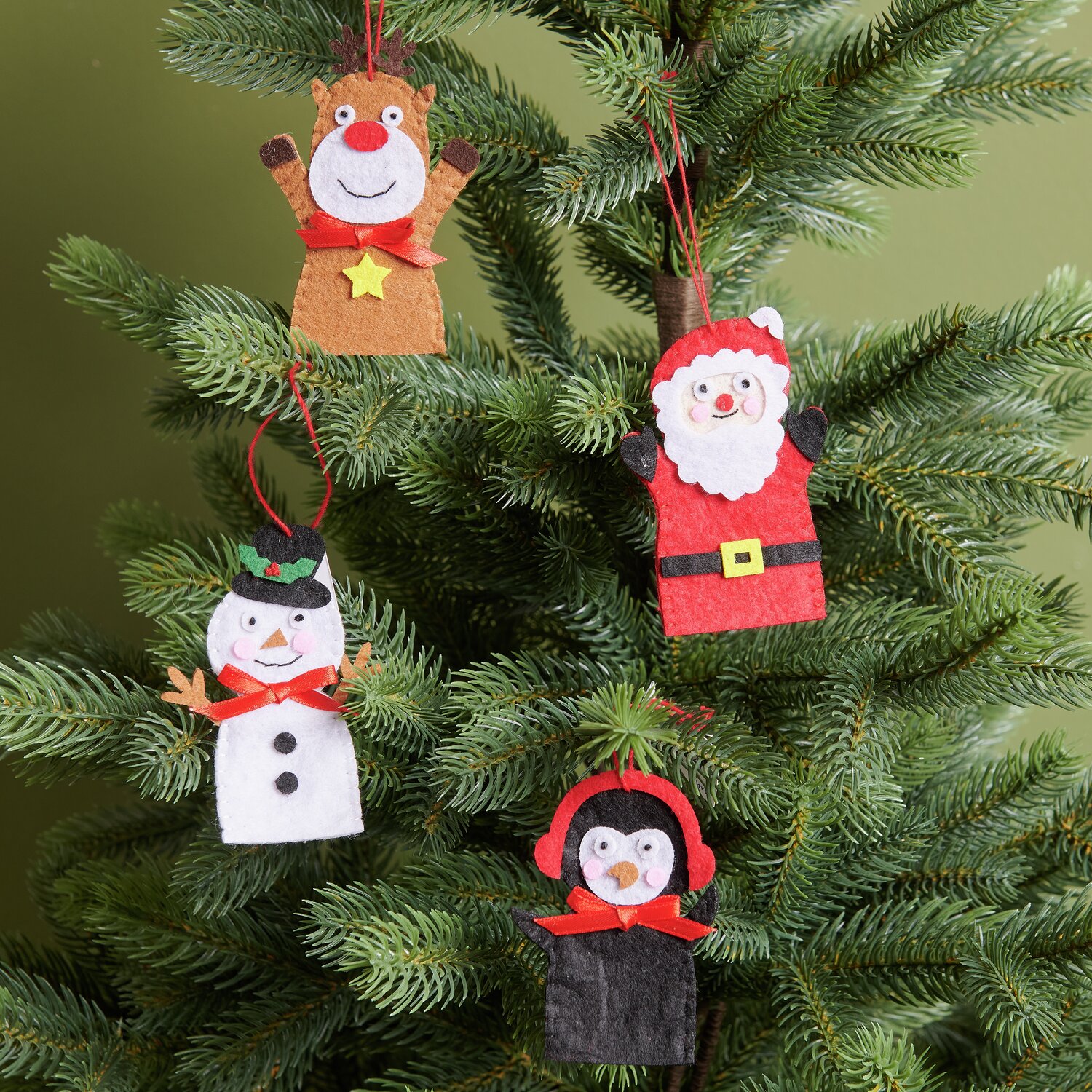 Aufhänger Filz-Rentier flach Braun, Weihnachtsmann, Pinguin und Schneemann aus Filz an einem grünen Tannenbaum.