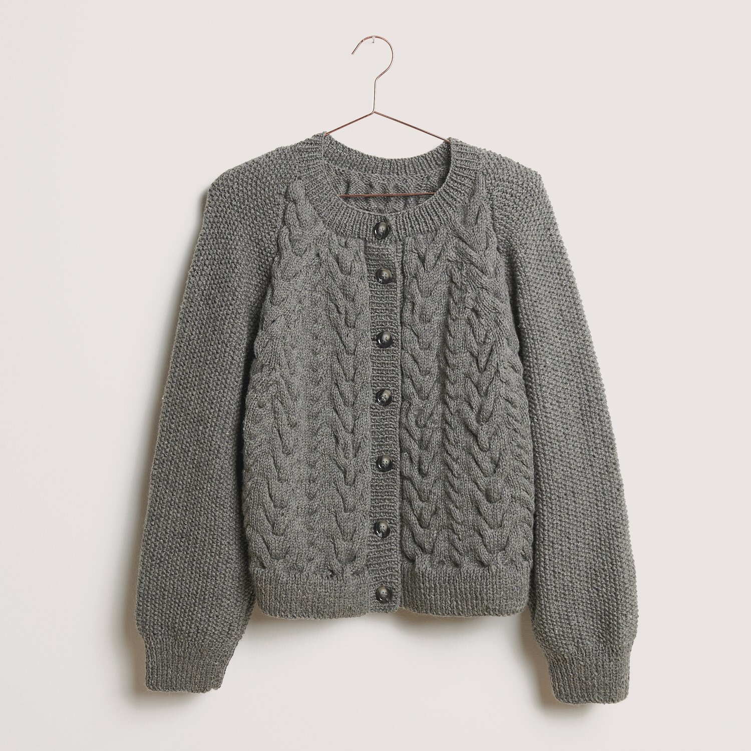 Die Neue Masche No. 14 Winter von idee. Creativmarkt Essentials Soft Merino aran Strickjacke in Mittelgrau mit Zopfmuster und Knopfleiste, ideal für kühle Tage.