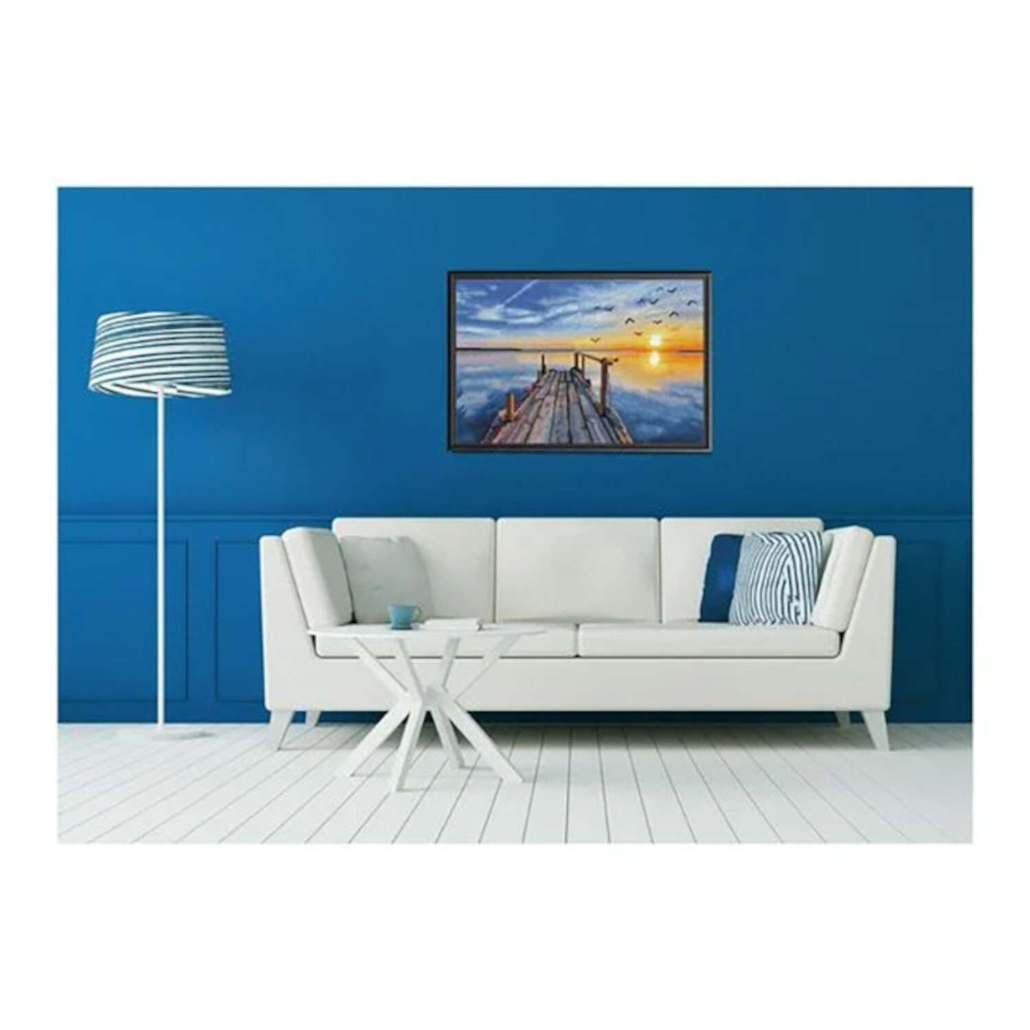 Diamond Painting Sonnenuntergang See: Wohnzimmer mit blauem Wandbild, weißem Sofa und passender Stehlampe.