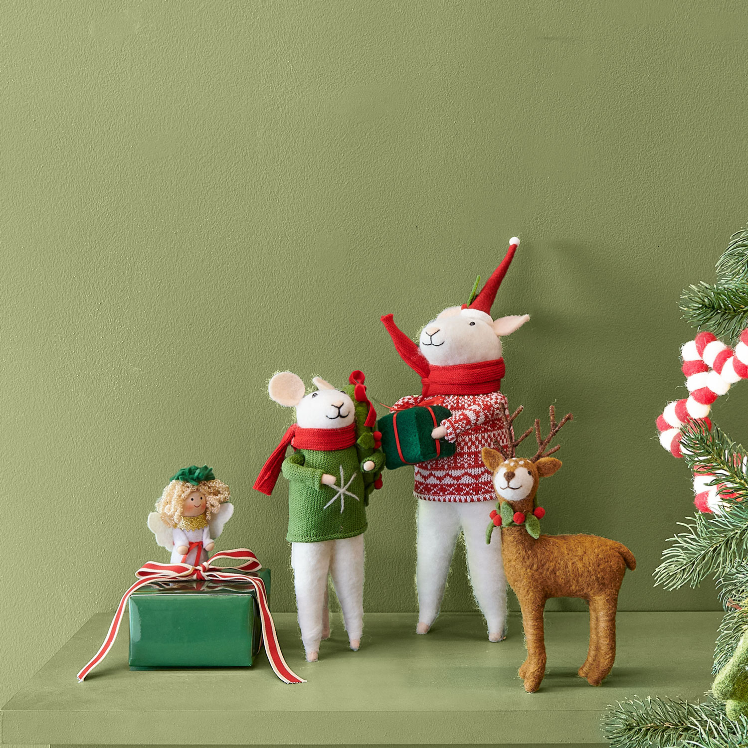 Zwei weihnachtlich gekleidete Filzmäuse, ein Filzengel und ein Filzrentier. Fotosetting grüner Hintergrund.