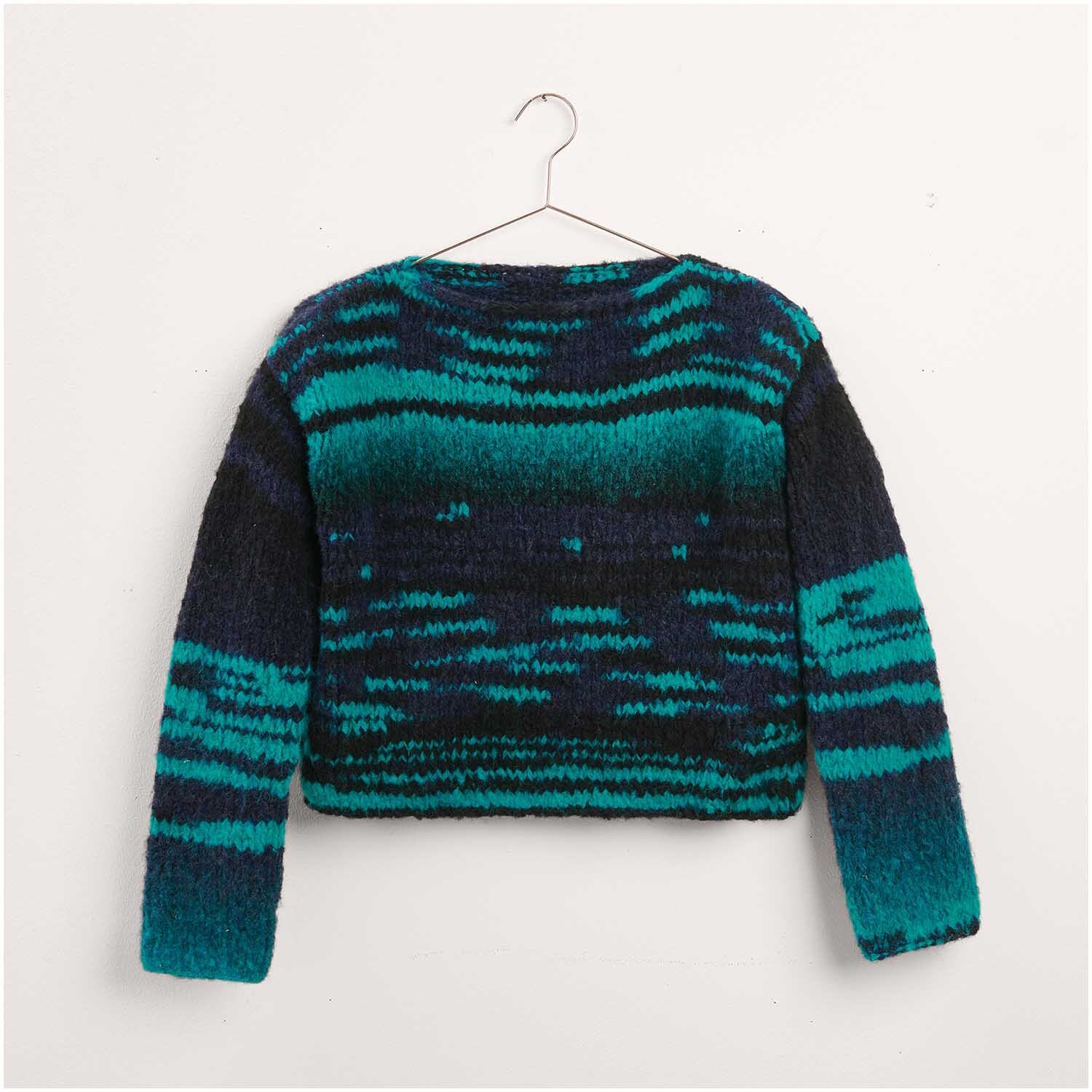 Pullover in Blau- und Grüntönen, gestrickt aus dem Strickset "Modell 43" von Made by Me Nr. 17. Auf einem Kleiderbügel präsentiert, zeigt das Modell Legeware ein einzigartiges Muster.