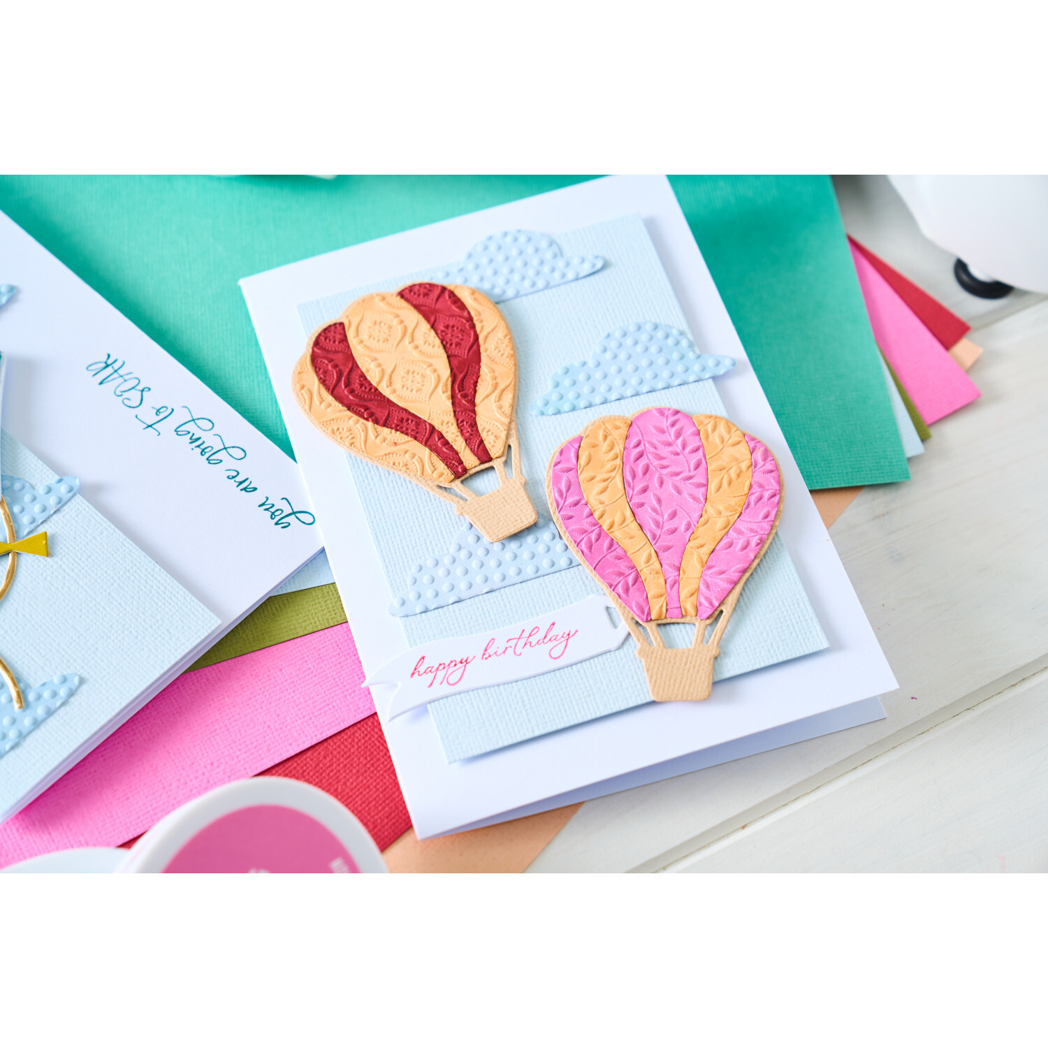 3D-Embossing Folder Textured Impressions Posh Patterns: Bunte Heißluftballons auf Grußkarte mit Sizzix-Prägung, umgeben von farbigem Papier.