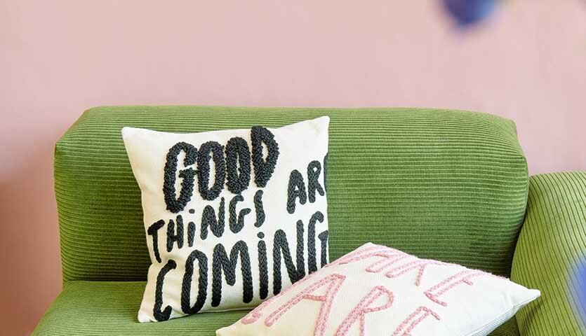 Anleitung Punch Needle Kissen mit Spruch Anleitung Punch Needle Kissen mit Spruch: Zwei dekorative Kissen auf grünem Sofa, eines mit schwarzem Text, das andere mit rosa Schrift.