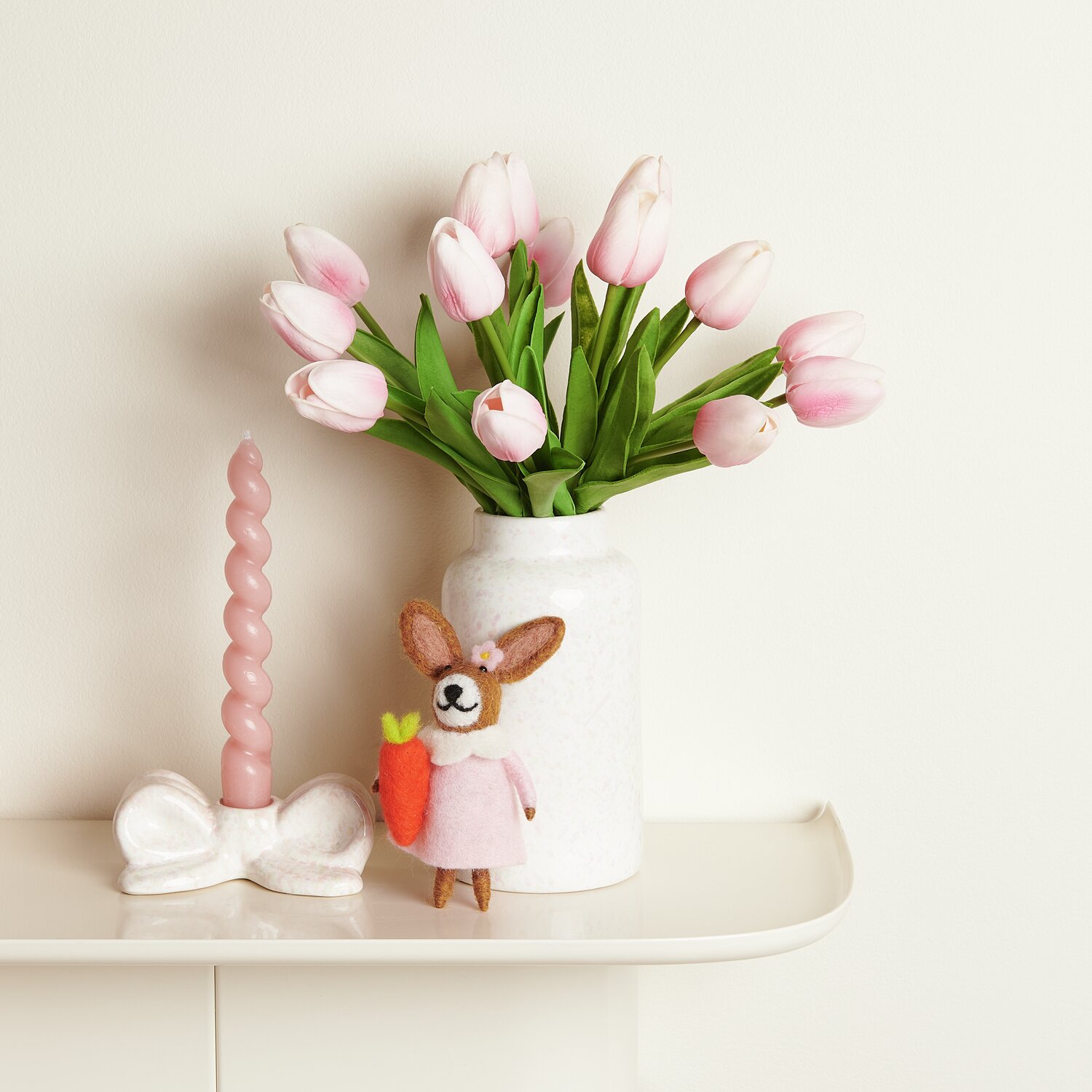 Aufhänger Filz-Hase mit Möhre und rosa Kleid vor Vase mit rosa Tulpen und gedrehter Kerze.