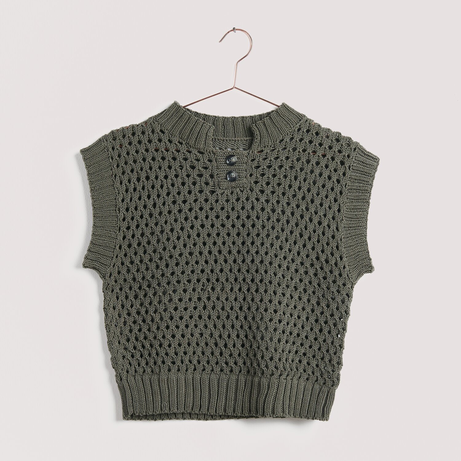 Strickset Top Modell 13 aus Die Neue Masche No. 15: Olivgrünes, ärmelloses Stricktop mit Knopfleiste, gehängt an einem Kleiderbügel.