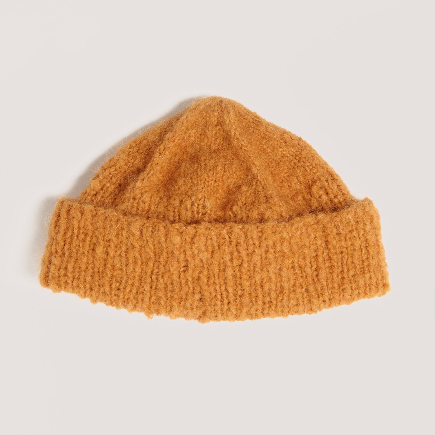 Strickset Mütze 13 aus Luxury Knits Little Pieces, weiche grobgestrickte Beanie mit breitem Umschlag, flach liegend auf hellem Hintergrund für Garn-Look.