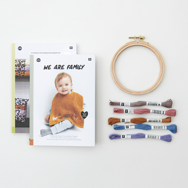 Zwei verschiedene Stickbücher übereinandergelegt und daneben liegen Stickgarne in mehreren Farben und ein Stickring aus Holz. Flatlay von Produkten.
