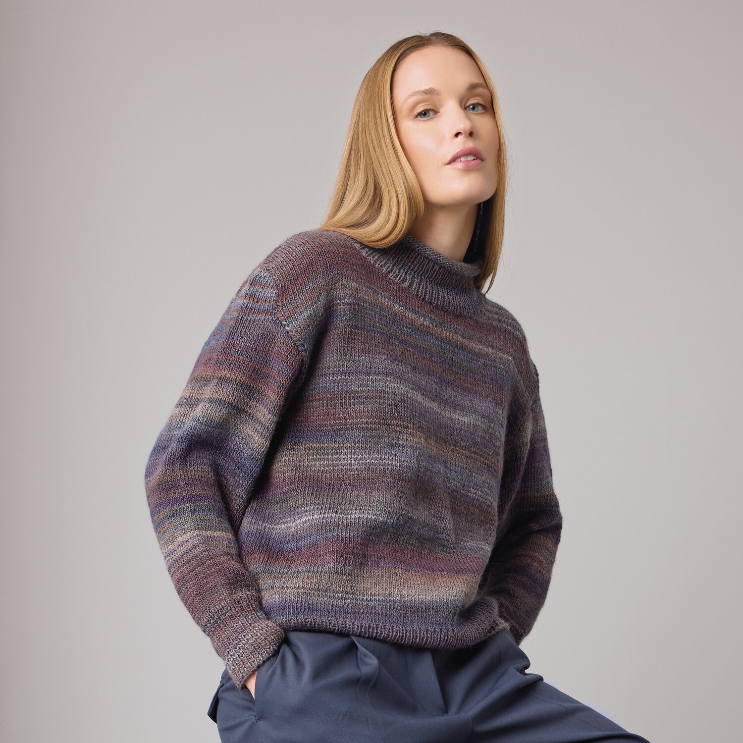 Strickset Pullover Modell 13 aus Die Neue Masche No. 14 von idee. Creativmarkt Strickset Pullover Modell 07 aus DNM 14: Frau trägt mehrfarbigen Pullover, kombiniert mit blauer Hose.