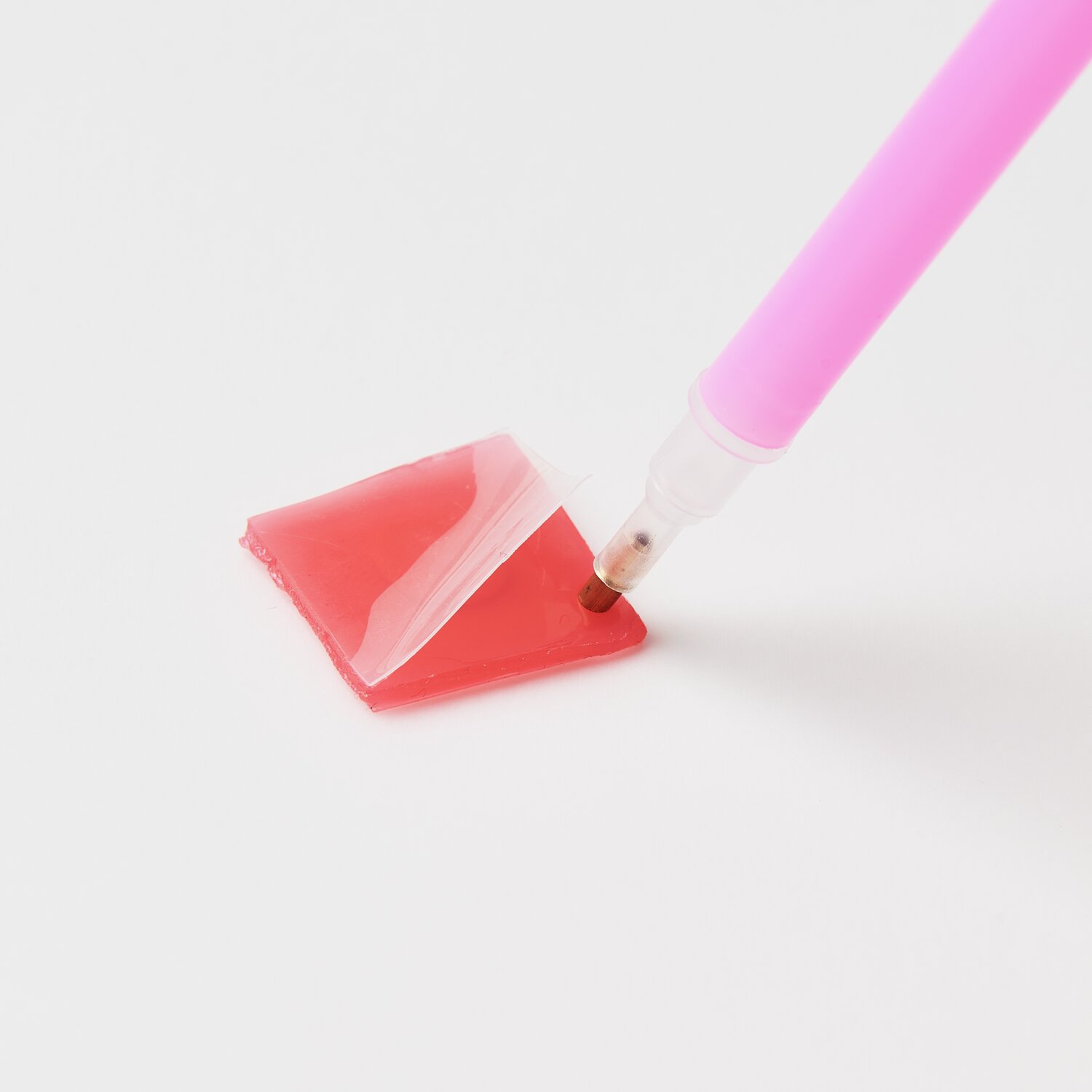 Diamond Painting Aufhänger Tiere, 29-teilig: Ein pinker Stift nimmt roten Kleber auf weißem Hintergrund auf.