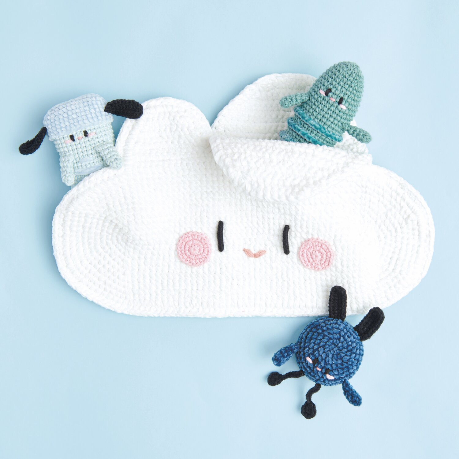 Ricorumi Rainbow Weirdos auf weißer Wolke mit rosa Wangen, umgeben von bunten Häkelmonstern.