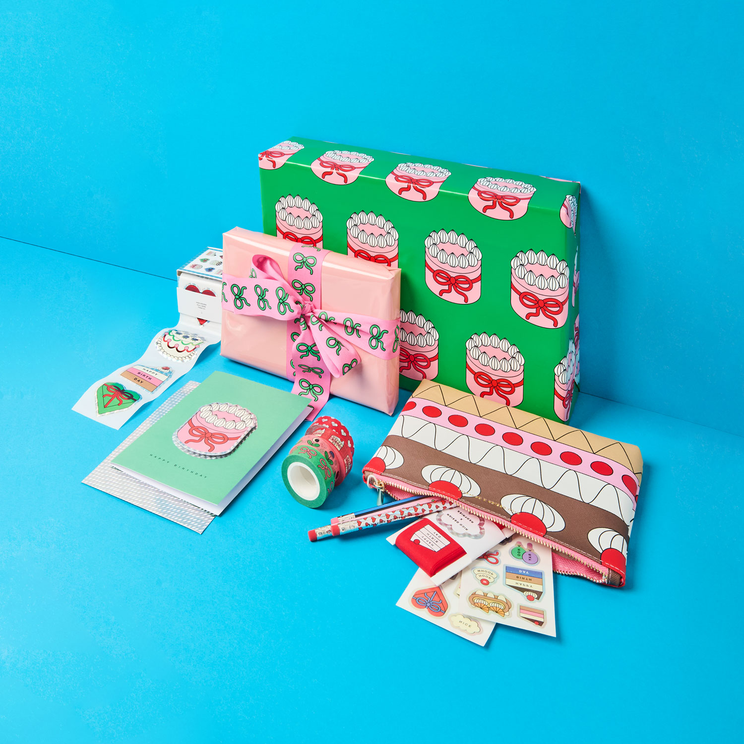 Zwei verpackte Geschenke, eine Geschenkkarte, Sticker und ein Etui mit Bleistiften, Washitapes und Geschenkband. Produkte aus der Kollektion Eye Candy.