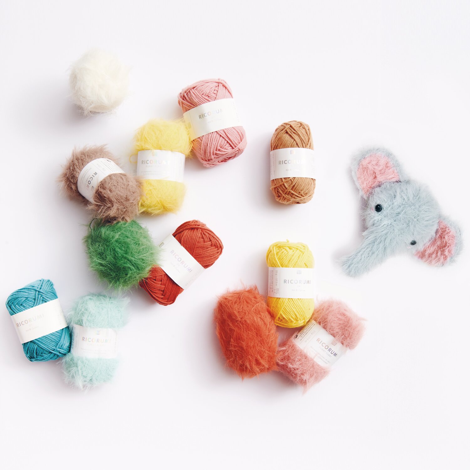 Ricorumi Furry Animals: Bunte Wollknäuel von Rico Design und ein gehäkelter Elefant auf weißem Hintergrund.