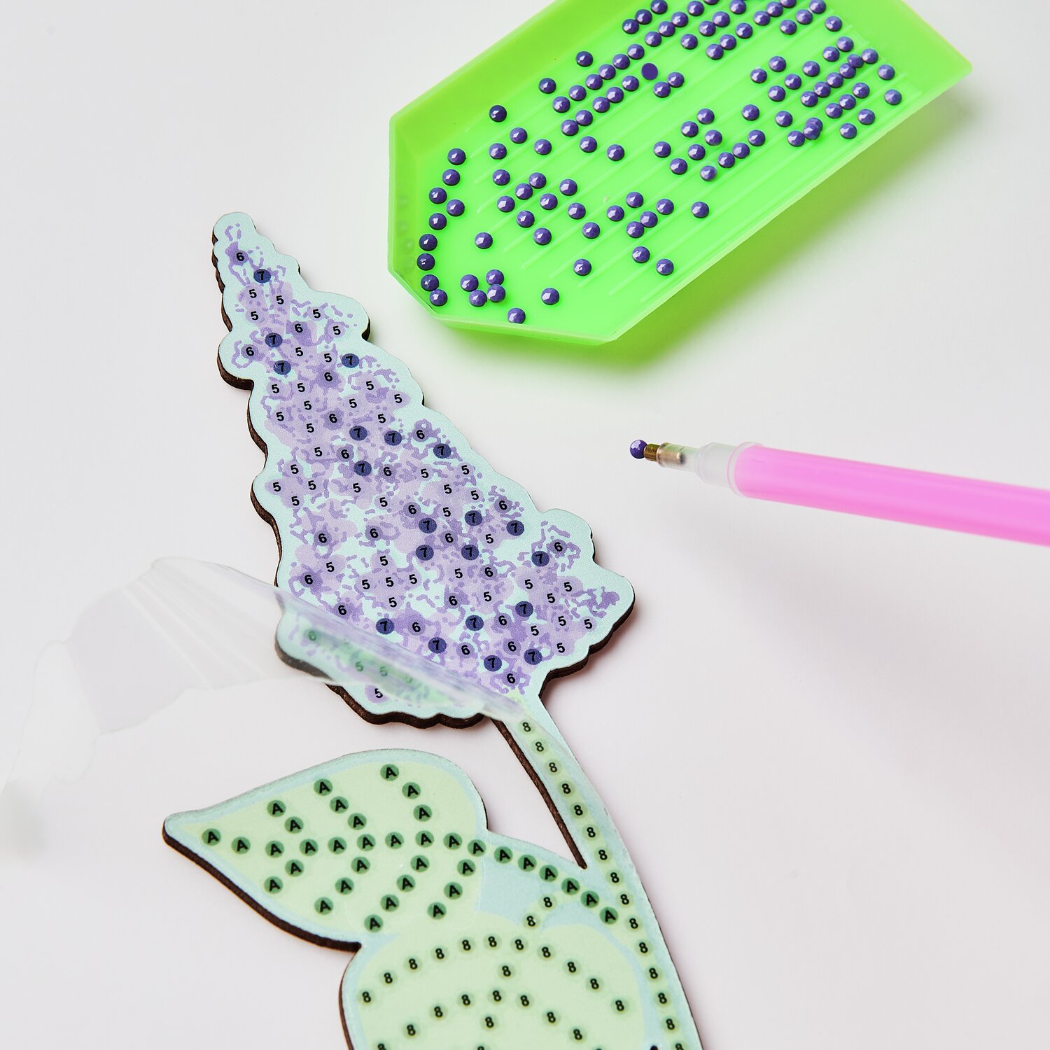 Diamond Painting DIY-Set Frühlingswiese 31x18,5cm, 26-teilig. Enthält grüne und lila Steine mit pinkem Stift auf weißem Hintergrund.