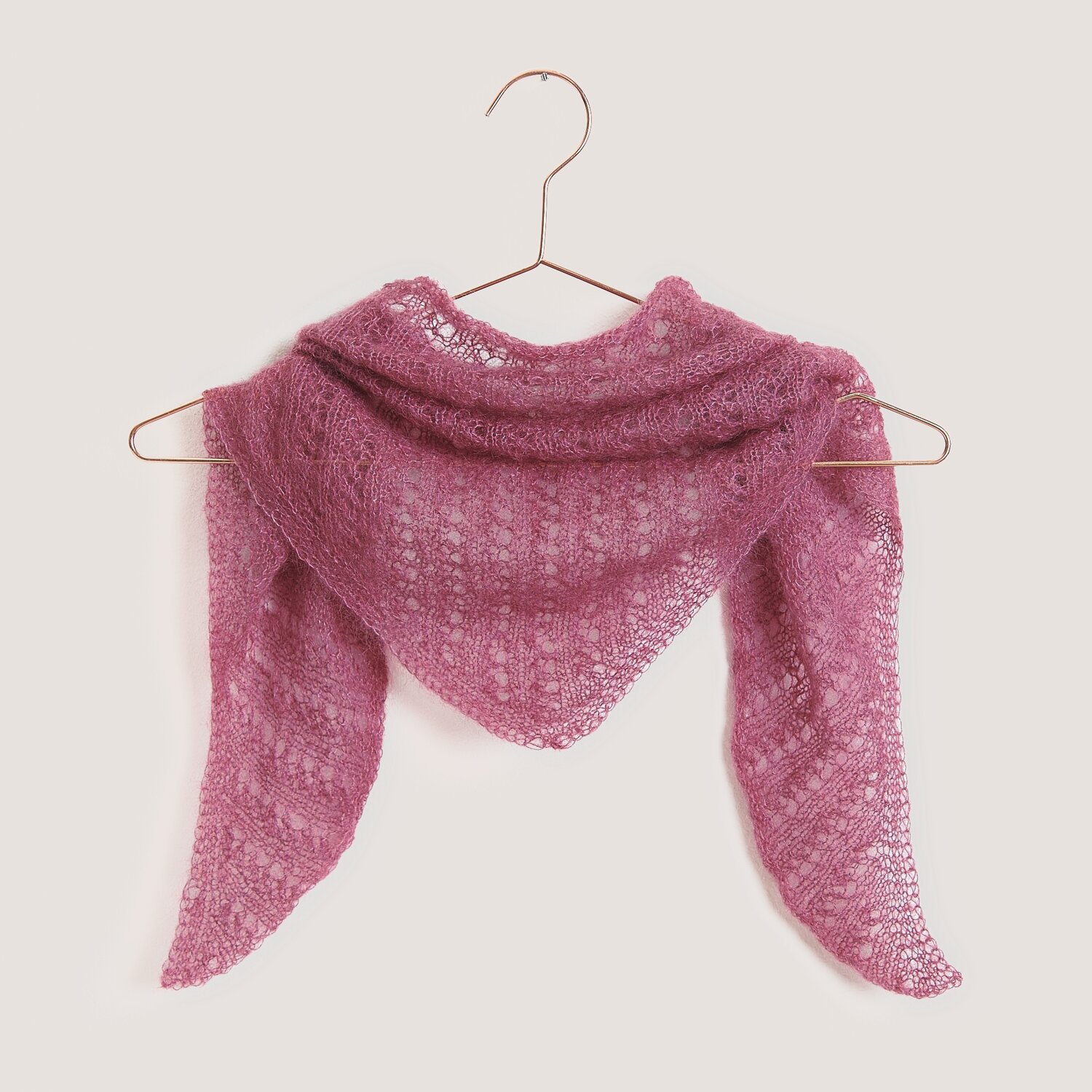 Strickset Dreieckstuch Modell 08 aus Tücher Special, lila, aus Essentials Super Kid Mohair Loves Silk, hängt auf einem Kleiderbügel.