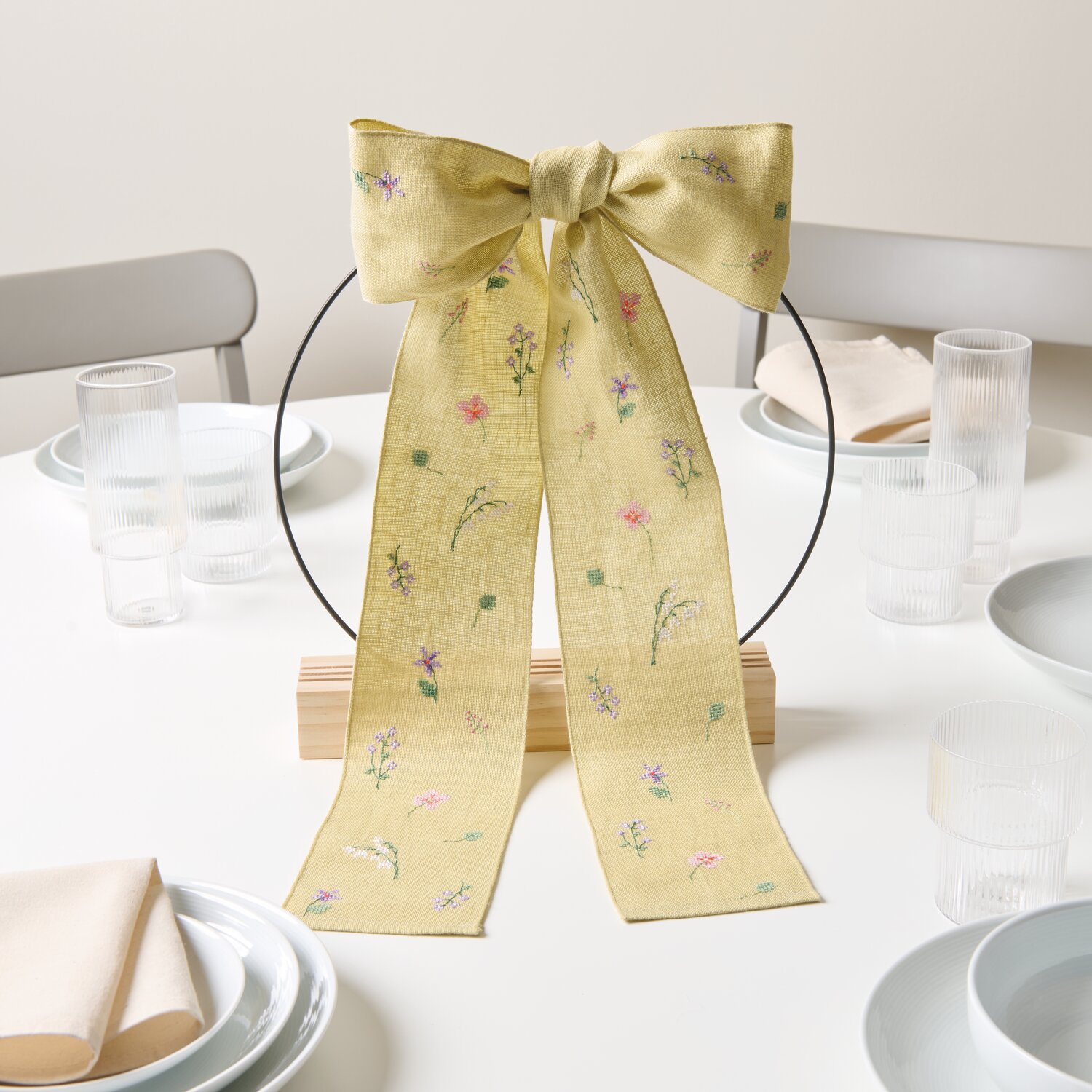 Stickpackung Gezählter Kreuzstich Schleife Wiesenblumen auf Tisch, dekoriert in Salbei.