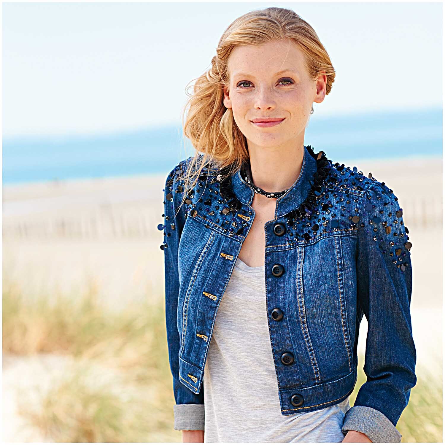 Glasschliff-Raute Perlen 6mm 12 Stück von Rico Design: Frau am Strand in Jeansjacke mit schwarzen Perlen verziert.