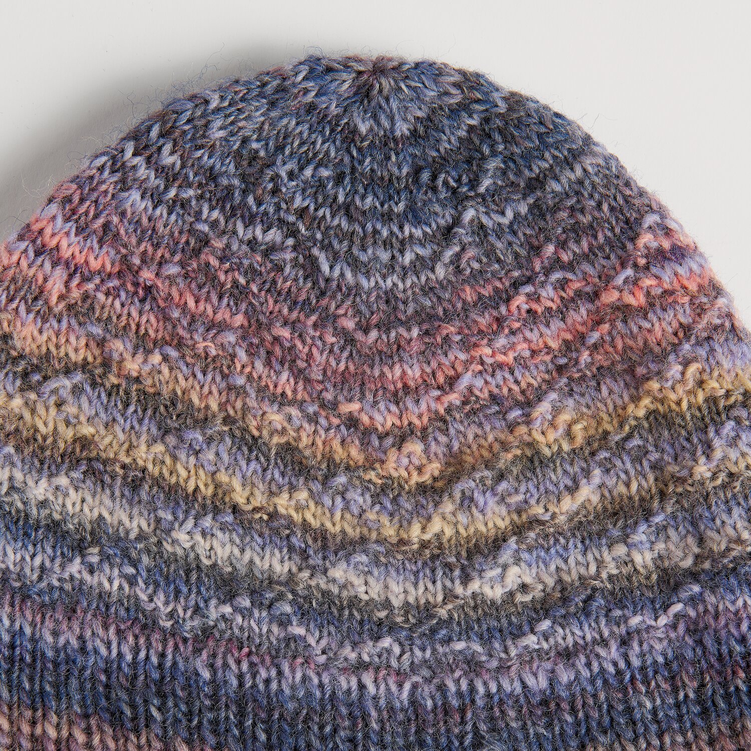 Die Neue Masche No. 16 Herbst zeigt eine gestrickte Mütze von Wolle Rödel mit fein verlaufenden Blau-, Rosa- und Beigetönen in dichter Struktur.
