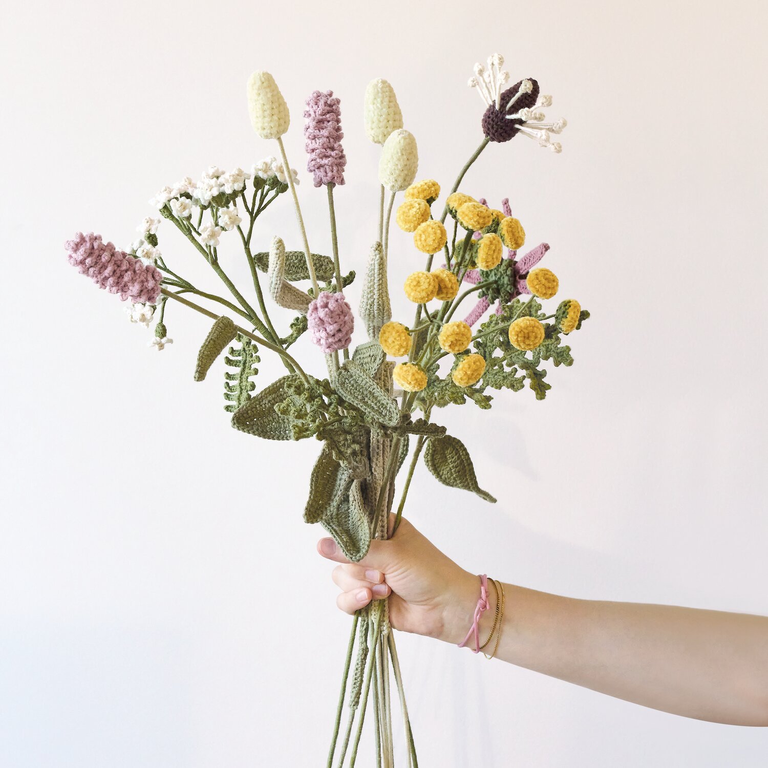 Ricorumi In the Meadow, gehäkelter Wiesenblumenstrauß aus Creative Ricorumi dk Garn von Rico Design in Naturtönen, gehalten von einer Hand, Knäuelgröße 25g
