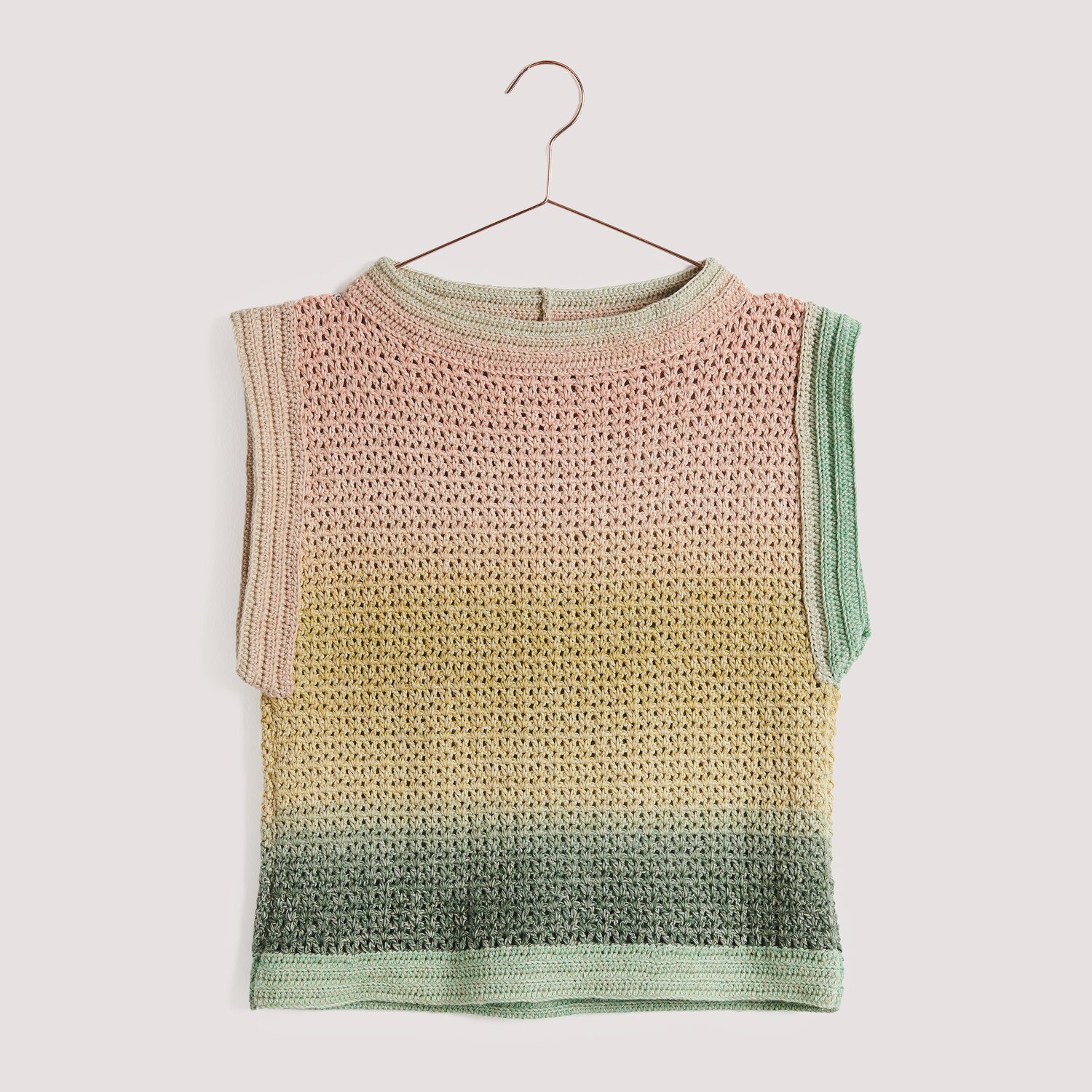 Häkelset Top Modell 09, gestricktes Oberteil in Pastellfarben, hängend an einem Kleiderbügel.
