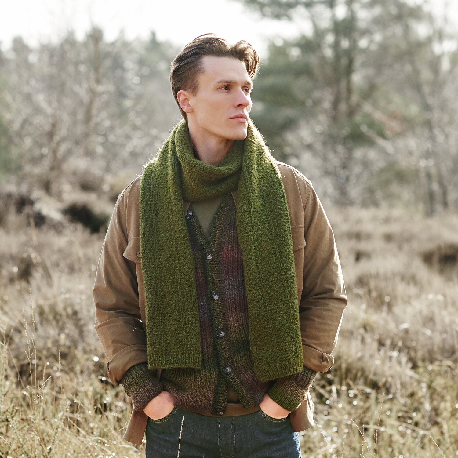 Strickset Schal Modell 12 aus Lovewool No. 21 von Rico Design Strickset Schal Modell 12 aus Lovewool No. 21: Mann trägt olivgrünen Schal in natürlicher Landschaft.