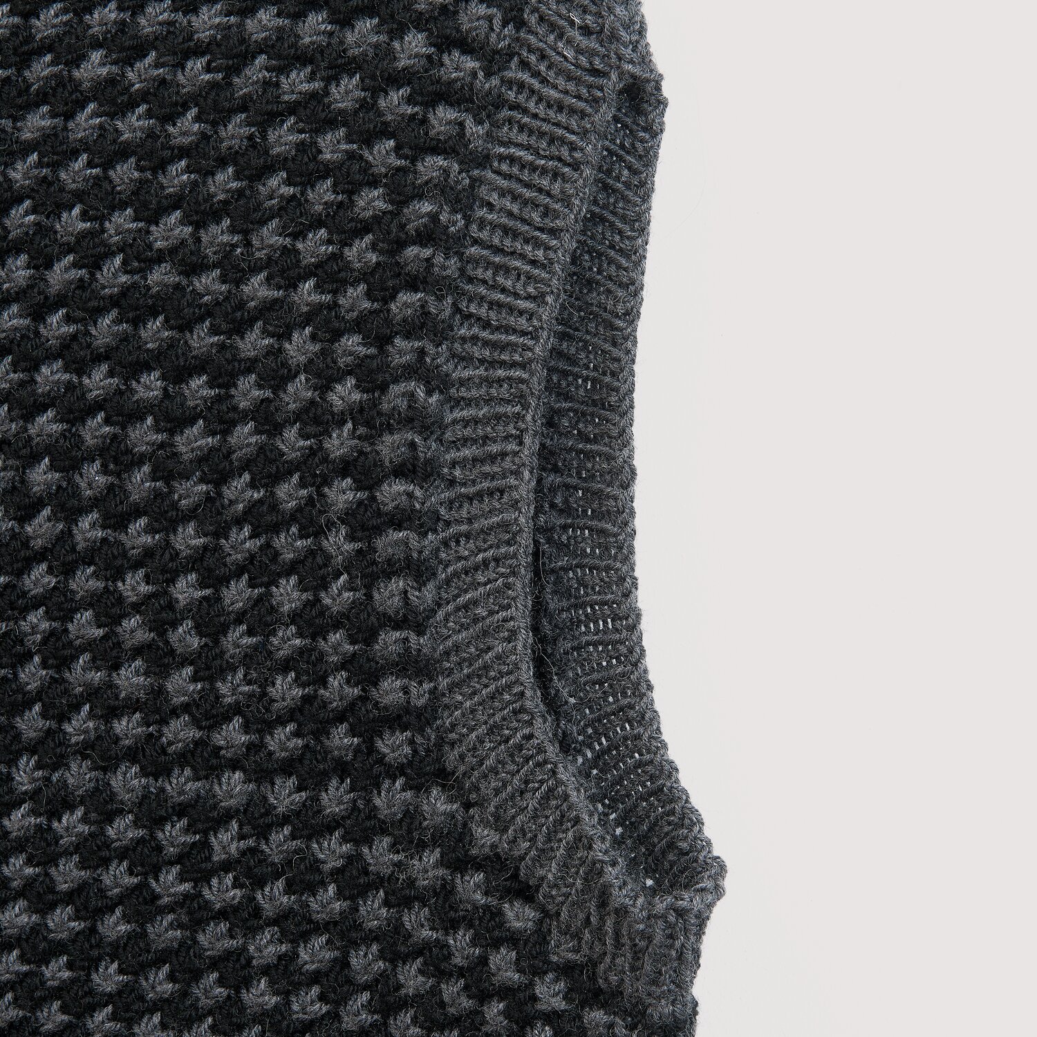 Die Neue Masche No. 16 Herbst zeigt einen gestrickten Wabenmuster-Pullover von Wolle Rödel mit kontrastierten Armausschnitten in dunklen Grautönen.