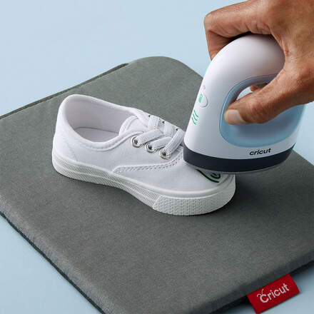 Mini-Press-Gerät wird von Hand gehalten und gestaltet weißen Kinder-Sneaker.