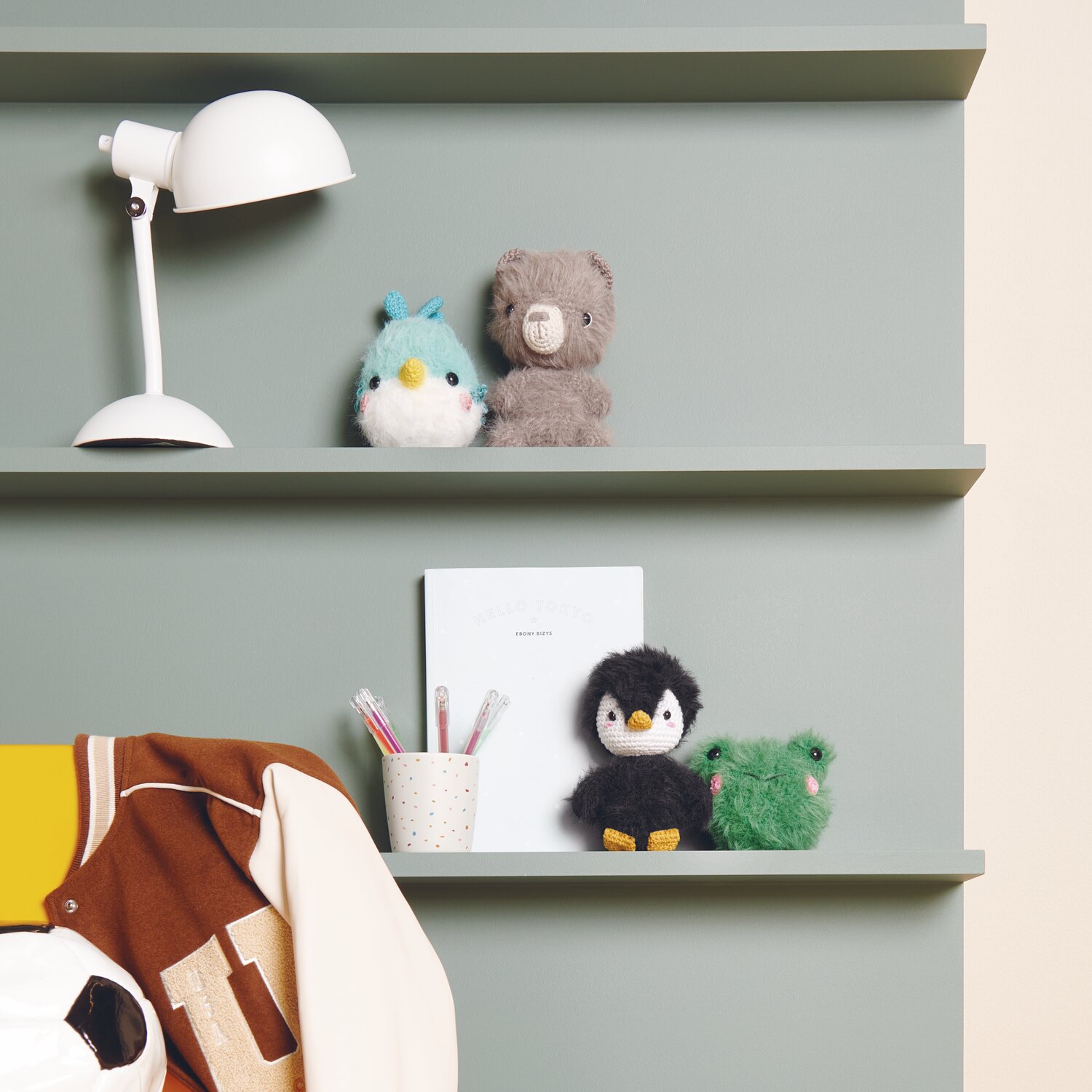 Creative Ricorumi dk 25g Farbe Tanne von Rico Design Ricorumi Furry Animals auf grünem Regal mit Lampe und Schreibutensilien, dekoriert mit Plüschtieren.