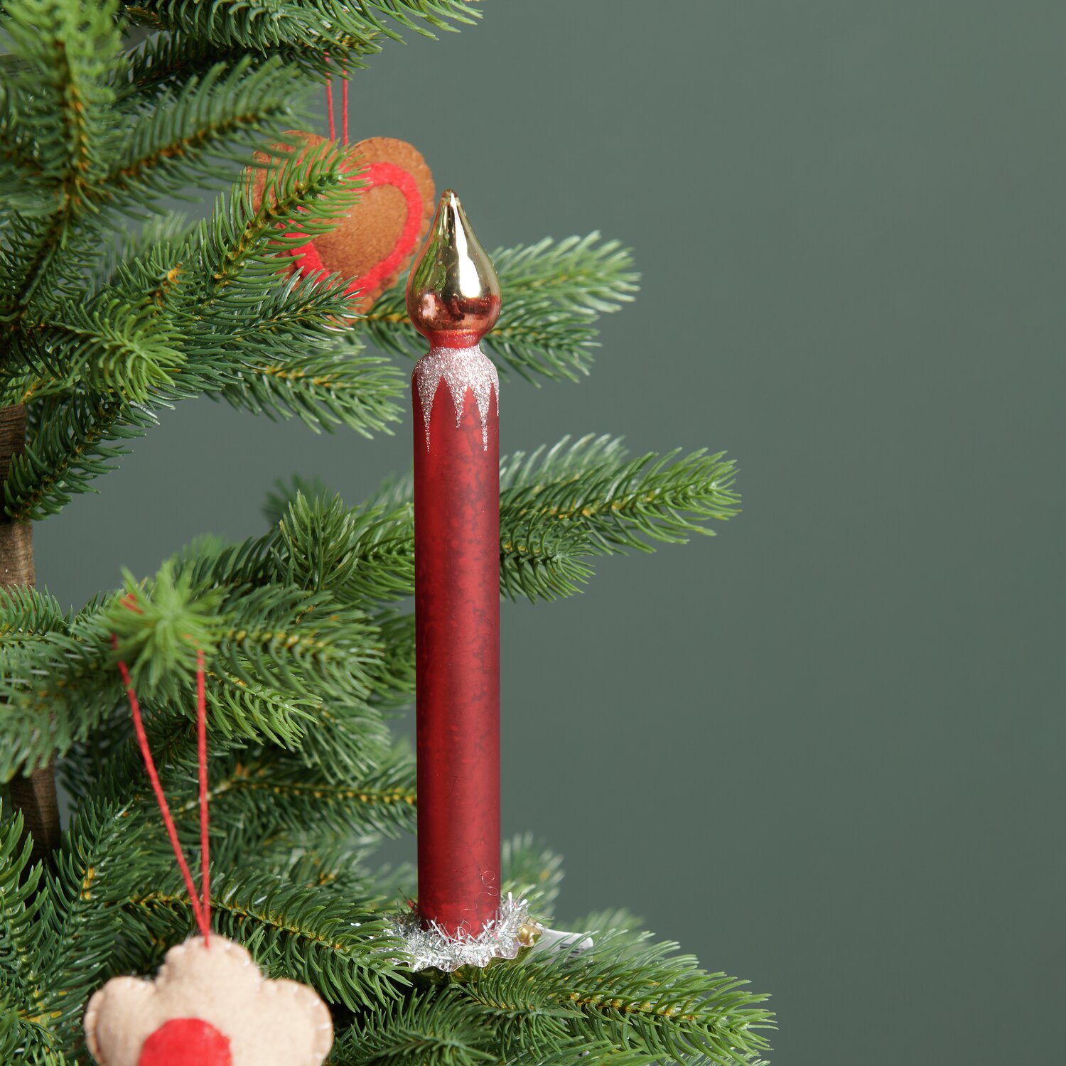 Baumschmuck Glaskerze mit goldenem Metallchip, rot, Ø2cm, hängt an einem grünen Tannenbaum.
