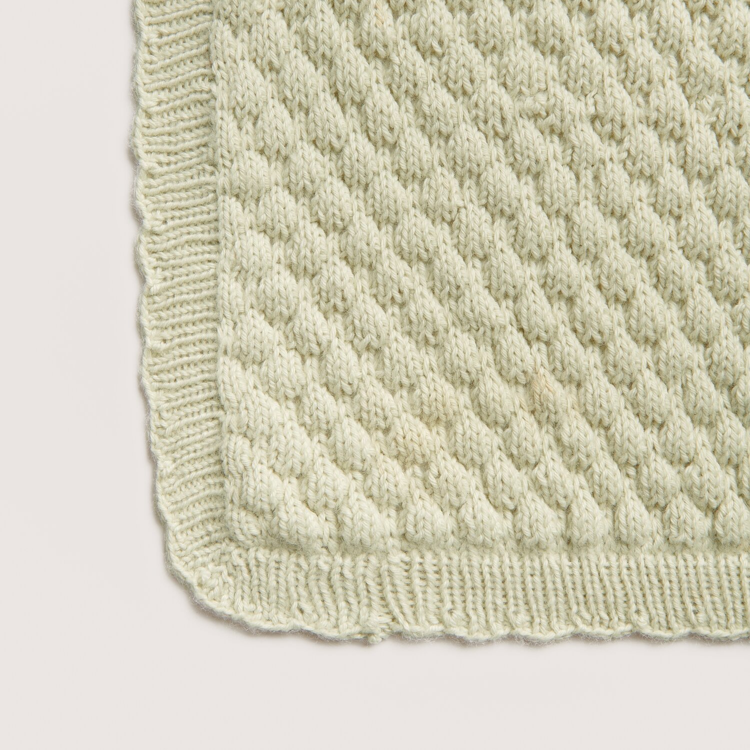 Rico Baby 042, gestrickte Decke in Salbei, zeigt ein strukturiertes Muster mit geripptem Rand. Ideal für Babyprojekte.